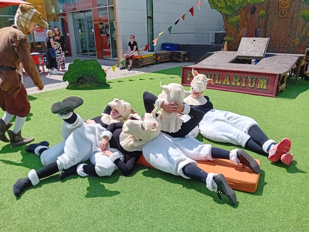 Four people dressed as sheep lying down